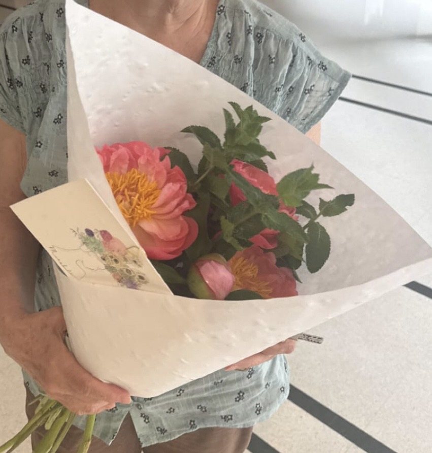 Bouquet de saison emballé dans du papier, tenu à bout de bras