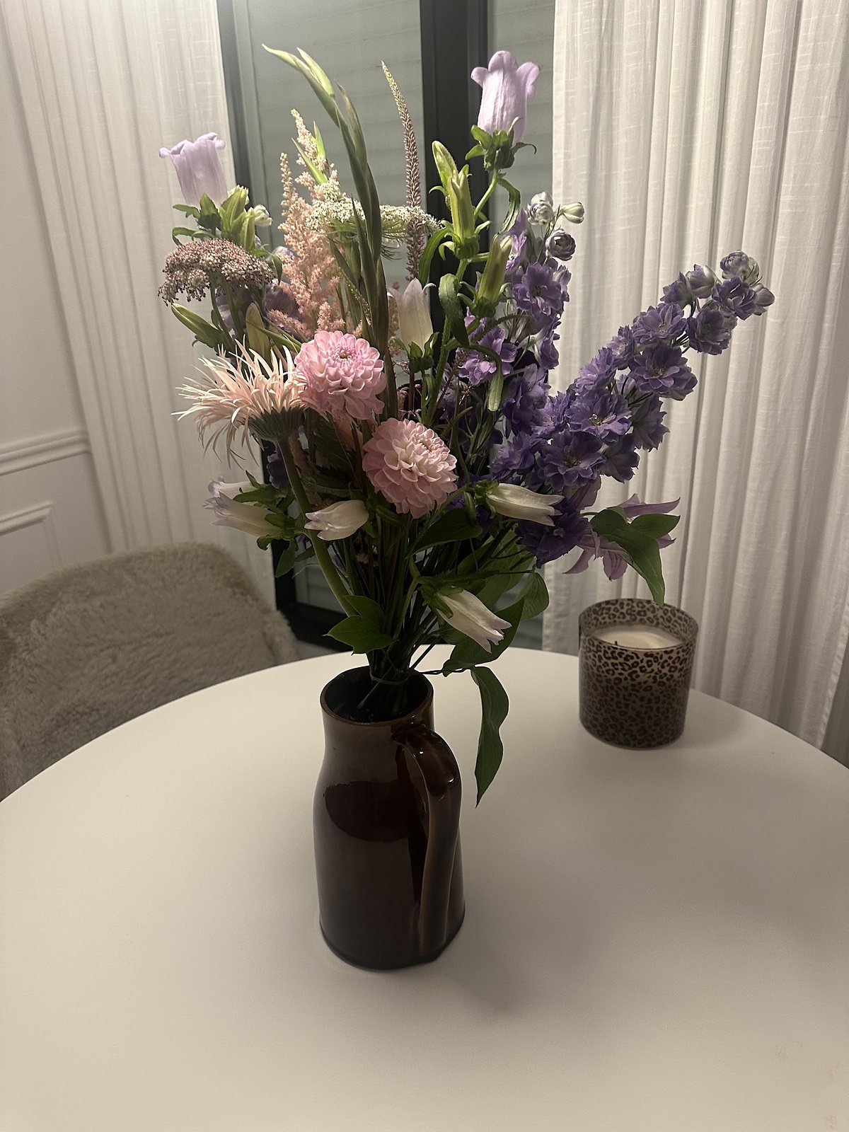 Bouquet haut de branches fleuries dans un vase sombre, sur une table ronde