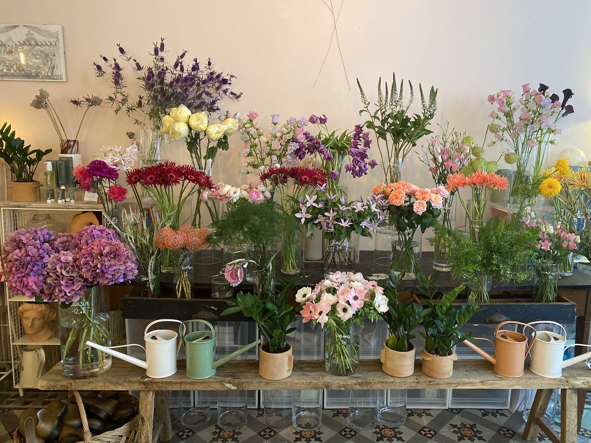 L’établi de la boutique, garni de fleurs de saison, d’arrosoirs et de pots en terre