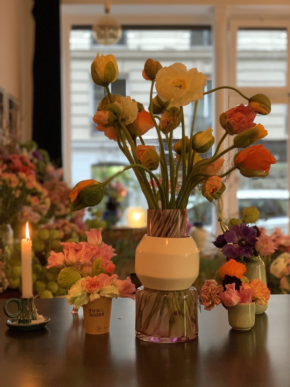 Bouquet de pavots orange dans un vase de verre, sur la table de la boutique, à côté d’une bougie