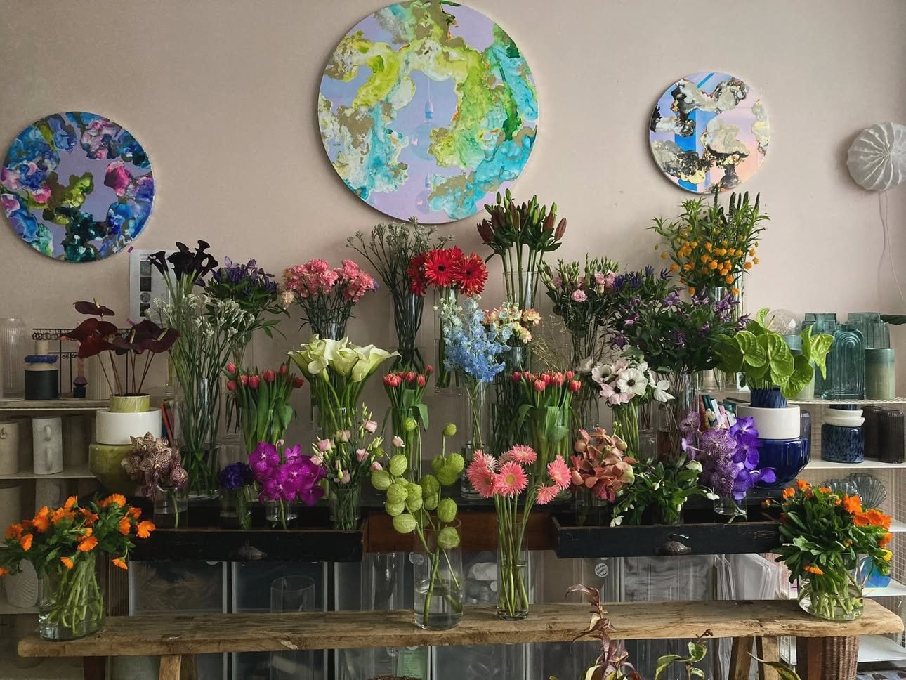 Œuvres rondes accrochées au mur au-dessus des seaux de fleurs et des céramiques