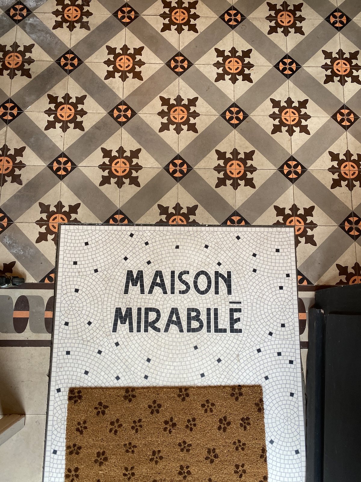 Le seuil de la boutique en mosaïque, au nom de la maison, sur les carreaux de ciment anciens